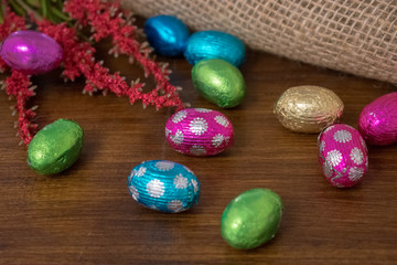 Obraz premium Colorful wrapped Easter eggs in rustic wooden and burlap background with copy space
