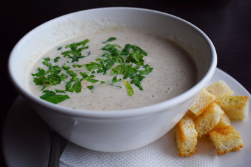 Delicious mushroom cream soup with crackers in a white plate.