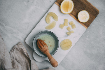 Lemons and citrus squeezer on a marble texture background with copy space