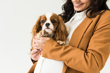 Cropped view of smiling pregnant woman holding dog isolated on white