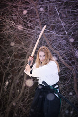 Obraz premium Female warrior. Woman with wooden sword practicing aikido in the snow