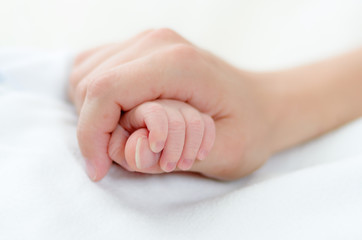 Mother holds babys hand