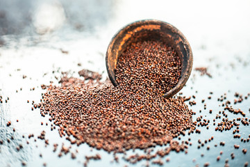 Raw organic herbal spice Mustard seeds or sarso or rai or Brassica nigra, in a clay bowl on wooden...