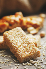 Sweets Bar of sesame on a vintage background with burlap. Delicious oriental sweets Gozinaki from sunflower seeds, sesame and peanuts, covered with honey with a shiny icing