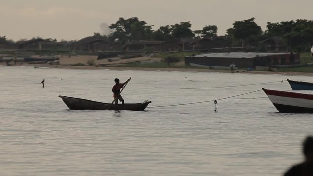Africa boy paddles canoe