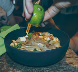 asian noodles dish being sprinkled with lime