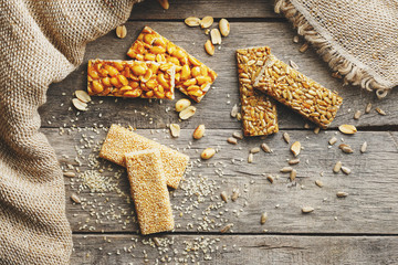 Mix of Gozinaki bar of seeds on a vintage background with burlap. Delicious oriental sweets from the seeds of sunflower, sesame and peanuts, covered with honey with shiny glaze. Macro Country Style