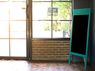 Blank black Chalkboard menu stand on floor near Window sill with door and brick wal