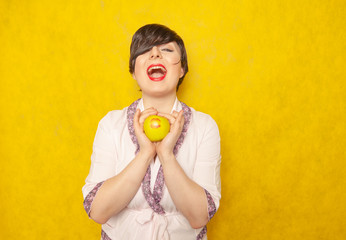 cute caucasian chubby woman with short black hair dressed in a pink cozy robe and holding a green Apple with a lipstick mark of a kiss