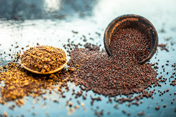 Raw organic herbal spice Mustard seeds or sarso or rai or Brassica nigra, in a clay bowl along with its powder in another bowl on wooden surface. - obrazy, fototapety, plakaty