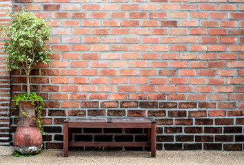 Sidewalk scene with wooden bench and red brick wall.