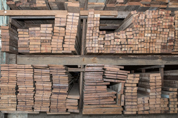 Piles of old wooden boards in the sawmill,  Warehouse for sawing boards on a sawmill indoors. Wood timber stack of wooden blanks construction material. Industry, Vintage styles