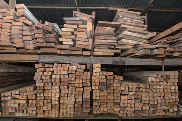 Piles of old wooden boards in the sawmill,  Warehouse for sawing boards on a sawmill indoors. Wood timber stack of wooden blanks construction material. Industry, Vintage styles