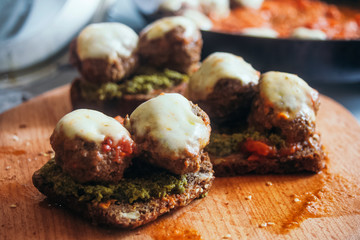 Sandwiches with meatballs in mozzarella cheese and pesto and tomato sauces.