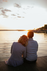 Fototapeta premium Girl and man sit on the edge of the lake and look into the distance