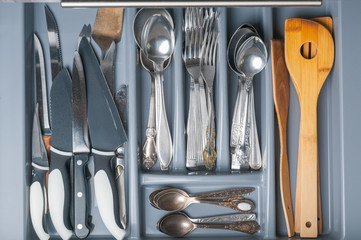 Opened kitchen drawer with cutlery. Top view
