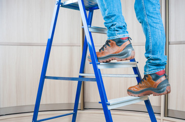 Handyman climbing on steel ladder indoor