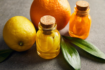 Essential oils with lemon and orange on dark surface