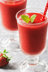 Close-up healthy vegan strawberry smoothie in glasses on a gray background. Summer strawberry smoothie. Selective focus.