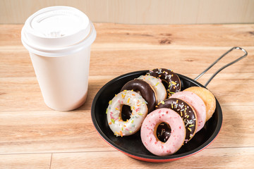 Donuts and drink and iron frying panon wood table background top view copy space pattern