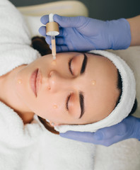 Obraz na płótnie Canvas beautician applying serum to female face. Serum treatment skin