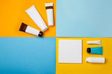Mock up summer skin care cosmetics on yellow and blue background. White bottles of woman cosmetics on yellow. Summer holidays or vacation. Preparation for summer care. Sunscreen protection  products