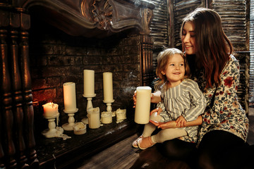 Fototapeta na wymiar Studio photo of mom and daughter near a fireplace
