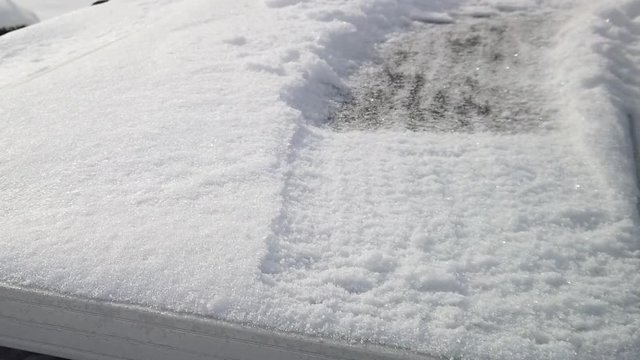 Someone brushing snow off of a solar panel at half speed