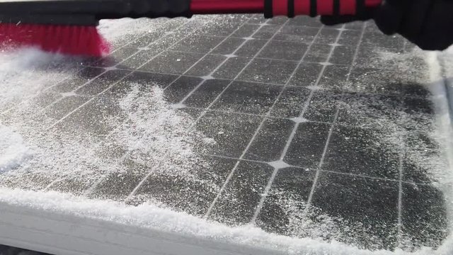 Someone brushing snow off of a solar panel at half speed