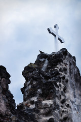 White cross on stone ruins with dramatic sky in Hermano Pedro, Antigua, Guatemala
