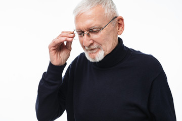 Old attractive man with gray hair and beard in eyeglasses and sweater thoughtfully looking aside while spending time over white background