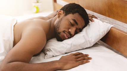 Fototapeta na wymiar Naked african-american man sleeping in bed closeup