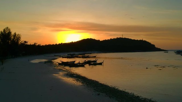 Aerial shot of beach during sunset with a Thai Boat