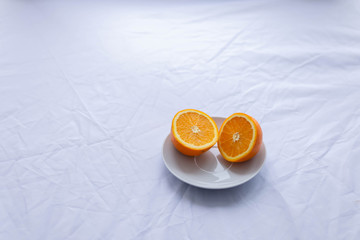 orange cut in half on white plate on white background