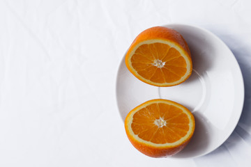 orange cut in half on white plate on white background