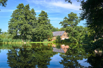 Fototapeta na wymiar Country landscape with a pond and the house in Poland.
