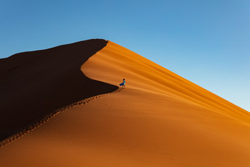 Fototapeta na wymiar Dunes at Sossusvlei National Park, Explorer Climbs Dunes