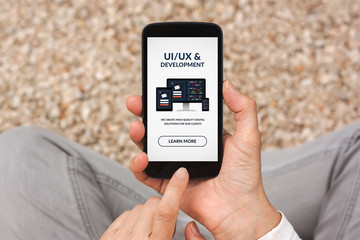 Hands holding smart phone with UI/UX design and development concept on screen