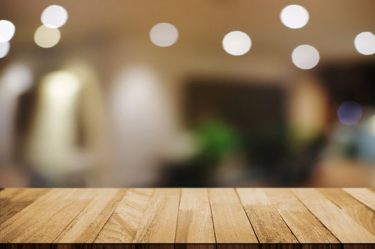 empty wood table top over blur night light in restaurant cafe background.