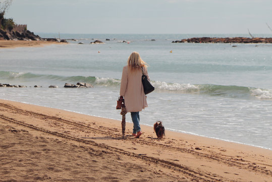 Woman with dog on walk on autumn beach. Santa Marinella, Italy
