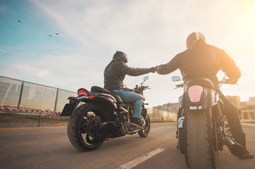 Two bikers ot motocycles handshaking with knuckle on road at sunshine