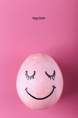 Pink egg with painted smiles. Happy Easter concept greeting card design.