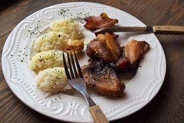 Roasted pork meat in bacon with rice on a white plate