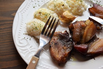 Roasted pork meat in bacon with rice on a white plate