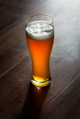 Glas Bier mit goldene Farbe im gegenlicht auf Holztisch