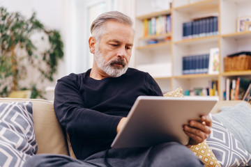 Senior man working on a tablet at home