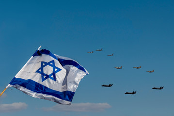 Streaming in the wind Israeli Flag and Military Defense Aircraft flying on blue sky on the Parade of Independence Holiday Day of Israel