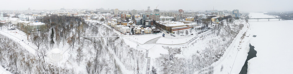 Obraz premium the city of Kirov and the high bank of the river Vyatka and the Alexander Grin Embankment and the rotunda on a cloudy winter day.