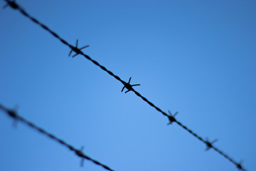 Barbed wired fence providing security to farmland in rural Hampshire set against a clear blue sky...