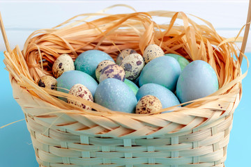 Easter composition with eggs in the basket on a blue and white background.
